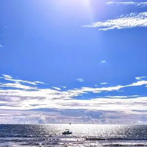 Open ocean and small boat under bright blue skies off the coast of Nosy Be, Madagascar