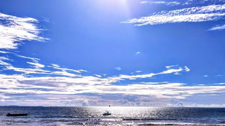 Open ocean and small boat under bright blue skies off the coast of Nosy Be, Madagascar