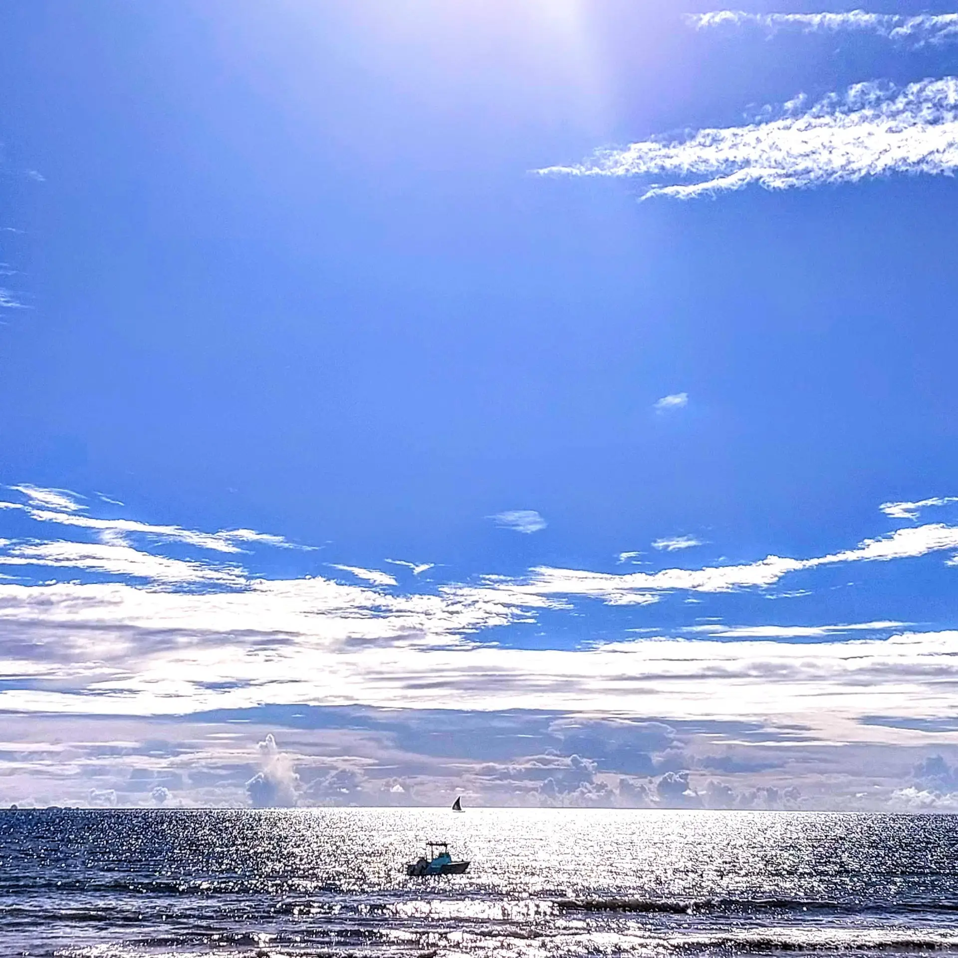 Open ocean and small boat under bright blue skies off the coast of Nosy Be, Madagascar