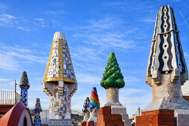 Colorful rooftop chimneys at Casa Milà (La Pedrera) in Barcelona under a bright blue sky on a sunny afternoon