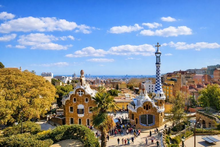 Park Güell in Barcelona with Gaudí’s iconic mosaic pavilions overlooking the city under a bright blue sky on a sunny afternoon