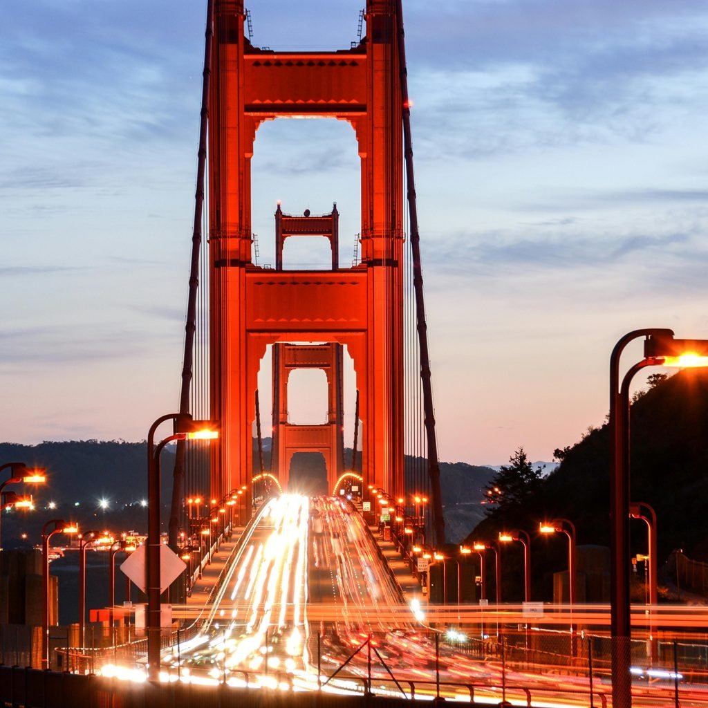 Golden Gate Bridge at dusk with glowing lights and long-exposure traffic trails in San Francisco