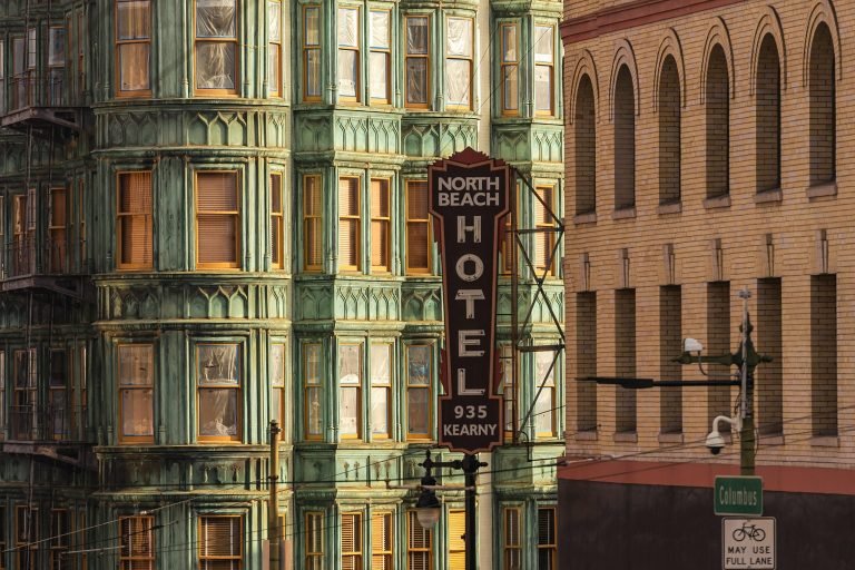 North Beach Hotel sign on Kearny Street in San Francisco with ornate green Victorian building facade in the background Caption: Description: