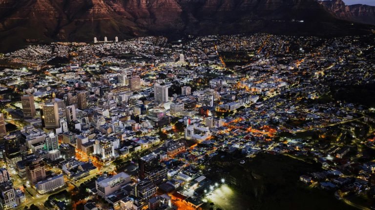 Aerial night view of Cape Town city center illuminated with streetlights and buildings beneath Table Mountain Caption: Description:
