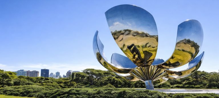 Floralis Genérica sculpture in Buenos Aires on a sunny day with bright blue skies and the city skyline in the background.
