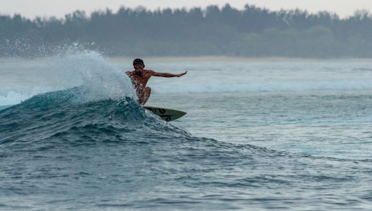 Surfer riding a wave in Bali during sunset - things to do in Bali