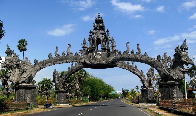 Traditional Balinese stone gateway along a road in Bali with blue sky - things to do in Bali