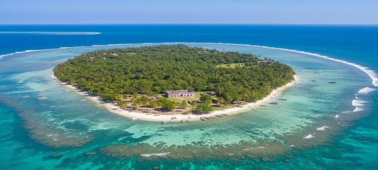 Aerial view of Kilwa Kisiwani Island surrounded by turquoise Indian Ocean waters and coral reefs off the coast of Tanzania. Caption: Description: