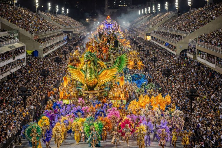 Things to do in Rio de Janeiro: Carnival parade at the Sambadrome in Rio de Janeiro with samba dancers in colorful feathered costumes and illuminated floats performing before a packed crowd at night
