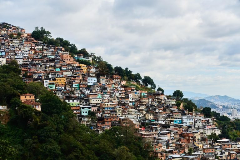 Hillside favela in Rio de Janeiro with densely packed colorful houses and city skyline in the distance Caption Description