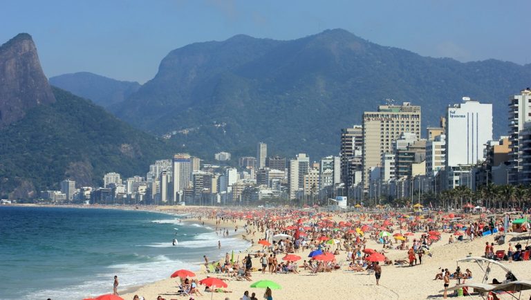 Crowded Ipanema Beach with Rio de Janeiro skyline and mountains featured in this things to do in Rio de Janeiro guide