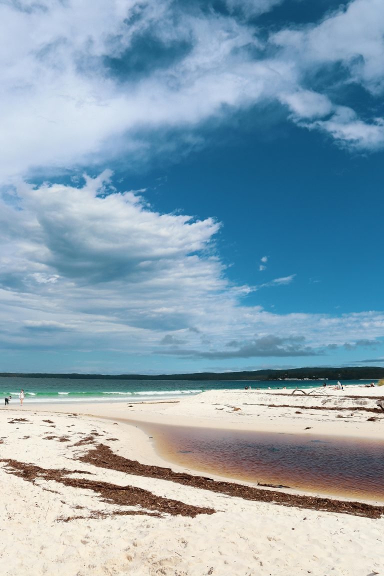Day Trips from Sydney: White sand beach with turquoise ocean and dramatic blue sky, New South Wales, Australia.