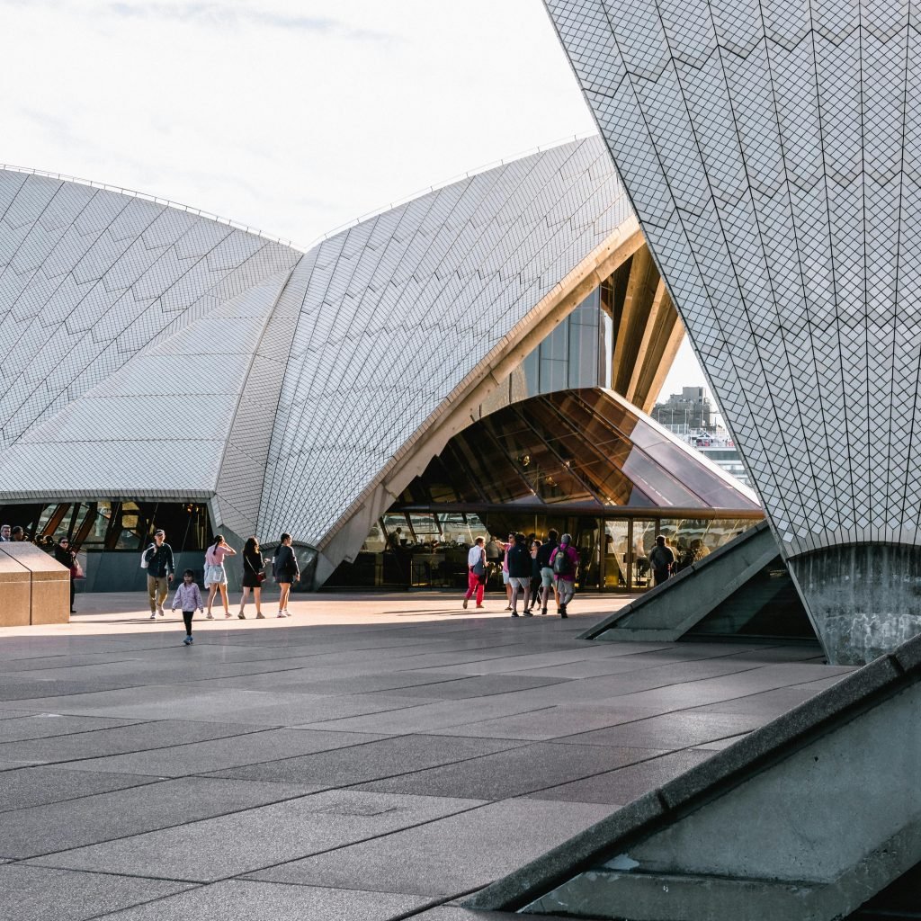 Sydney opera house tours tickets: Sydney Opera House close-up showing the iconic tiled sails and visitors walking around the forecourt in bright daylight.