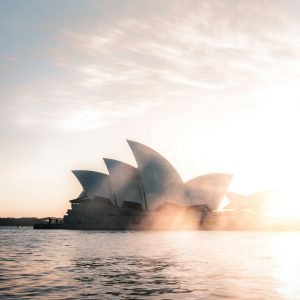 Sydney Opera House at sunrise with soft golden light reflecting over Sydney Harbour.