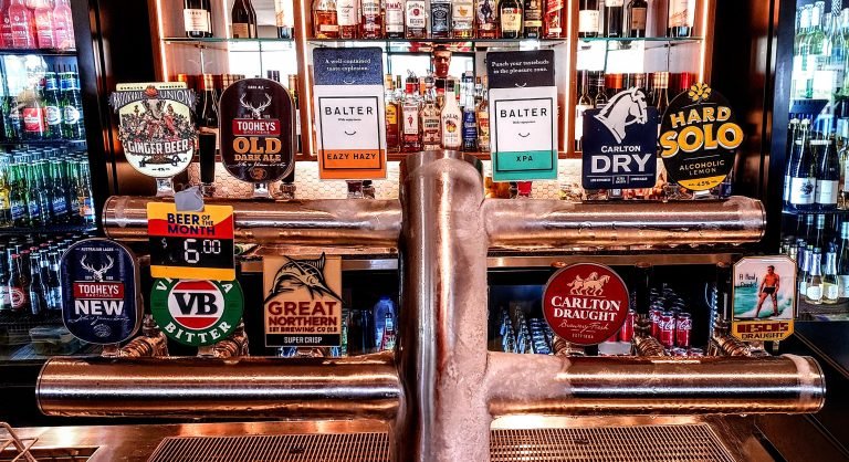 Beer taps and liquor bottles behind a pub bar in Sydney, featuring Australian brands like Balter, Carlton Dry, Tooheys Old, Great Northern, and Carlton Draught.