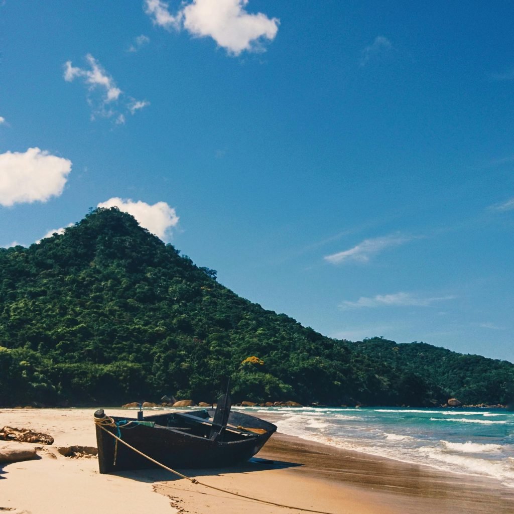 Small fishing boat on a quiet beach surrounded by forested hills near Rio de Janeiro