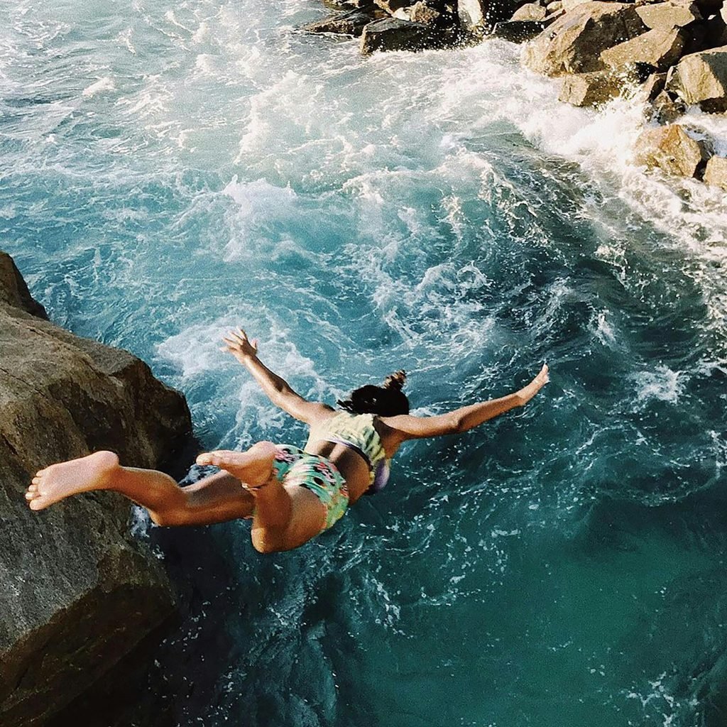 Person jumping from rocks into the ocean along the Rio de Janeiro coastline