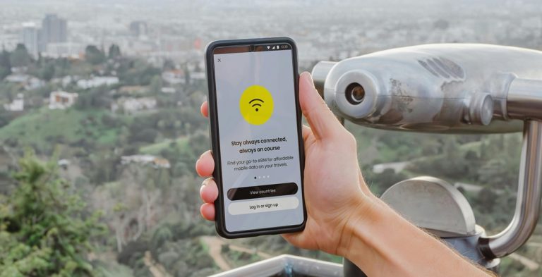 Traveler holding a smartphone with an eSIM app overlooking Rio de Janeiro from a scenic viewpoint