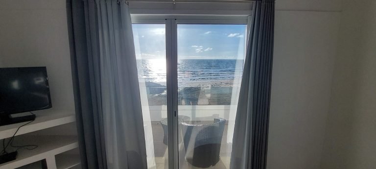 Ocean view from a hotel bedroom in northern Madagascar, with sunlight reflecting on the sea beyond a private balcony.