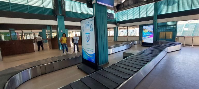 Interior of Nosy Be airport in northern Madagascar, showing the baggage claim area with conveyor belts and waiting passengers.