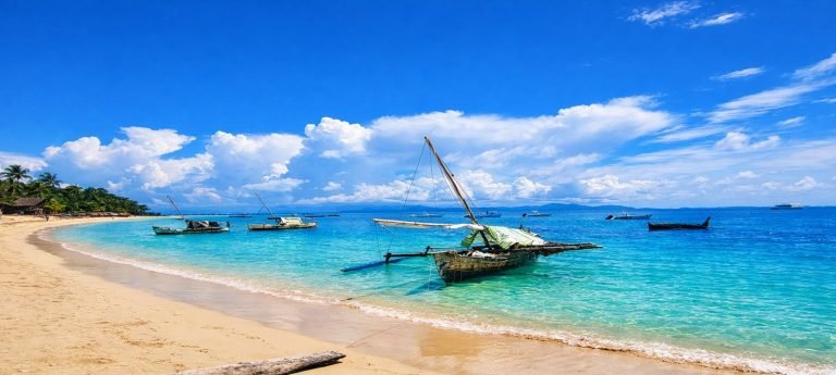 Sunny tropical beach in Madagascar with traditional fishing boats on turquoise Indian Ocean water under bright blue skies