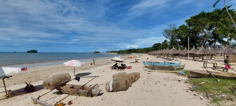 Madagascar Beaches - Andilana Beach in Nosy Be, Madagascar, with white sand, fishing boats, woven fish traps, and palm-lined shoreline