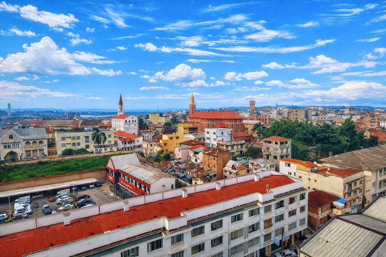 Panoramic city view of Antananarivo, Madagascar with colorful buildings, churches, and a bright blue sky