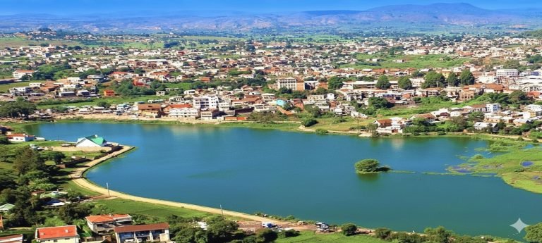 Aerial view of Antsirabe with Lake Tritriva in the foreground, surrounded by red-roofed houses and green hills in Madagascar’s Central Highlands.
