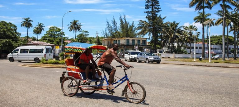 Getting around Madagascar: Cyclo-pousse transporting passengers along a street in Madagascar, a common form of local urban transport.