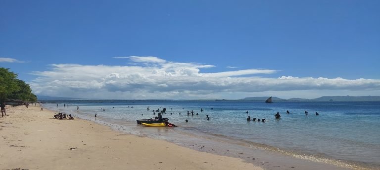Ramenas Beach near Diego Suarez with calm blue water and locals swimming along the sandy shoreline