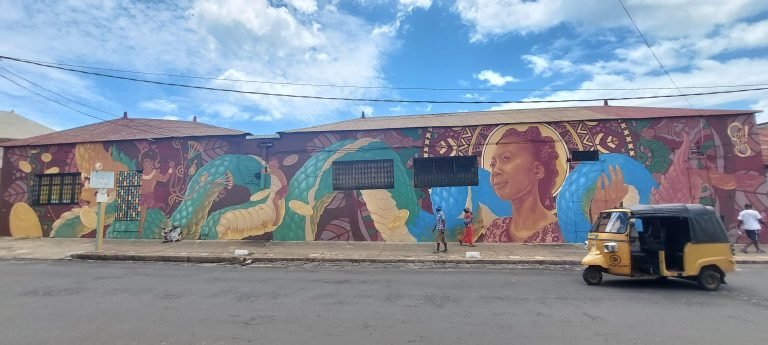 Colorful street art mural in Diego Suarez depicting a Malagasy woman, snake, and symbolic patterns along a city street