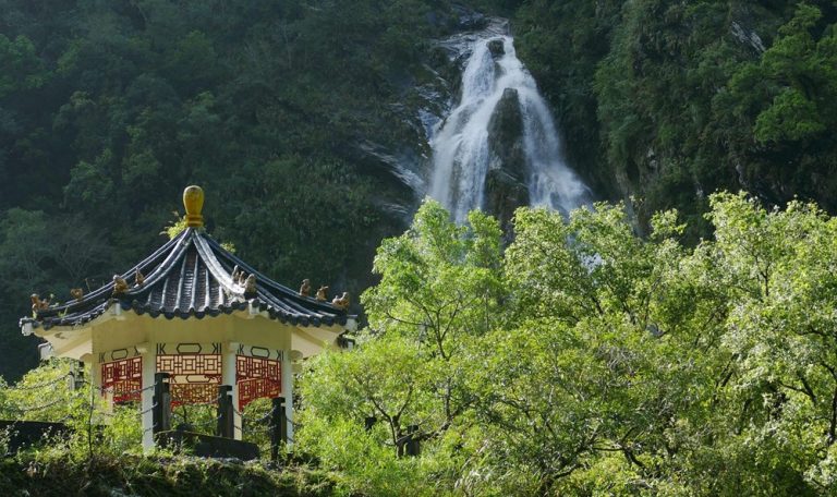 Eternal Spring Shrine in Taroko Gorge Taiwan with waterfall cascading through the mountains behind the pavilion
