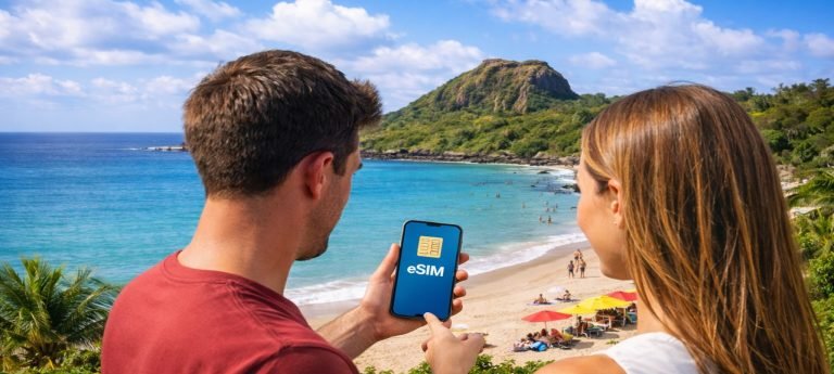 Two travelers overlooking a tropical beach in Kenting, Taiwan, holding a smartphone displaying an eSIM icon.