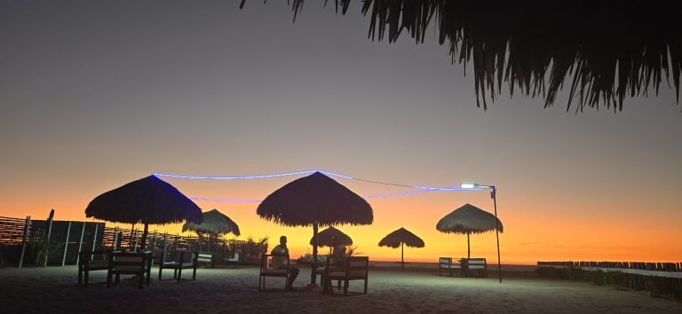 Sunset at a beach bar in Majunga, Madagascar with palapas, string lights, and ocean views.