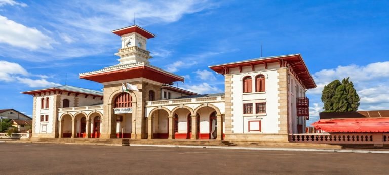 Antsirabe railway station with colonial red-and-white architecture under a bright blue sky in central Madagascar
