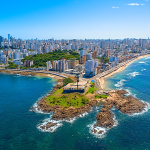 Aerial view of Salvador, Brazil showing the coastal peninsula, Atlantic Ocean, and city skyline under clear blue skies