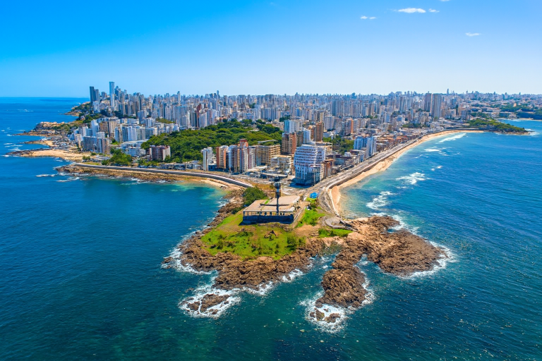 Aerial view of Salvador, Brazil showing the coastal peninsula, Atlantic Ocean, and city skyline under clear blue skies
