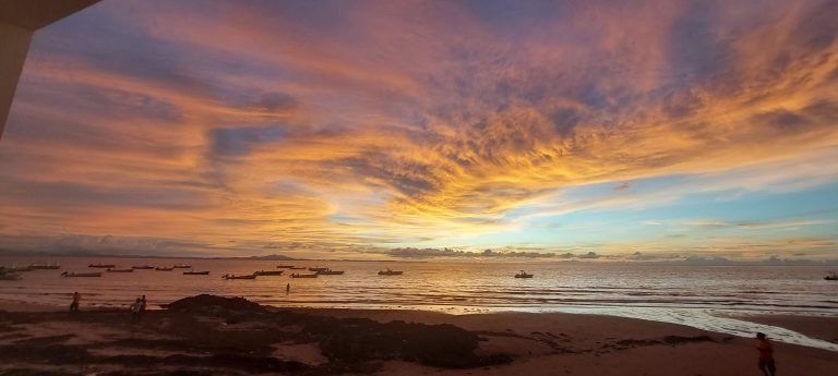 Sunset over the sea in Nosy Be, Madagascar, with fishing boats anchored offshore and dramatic evening clouds