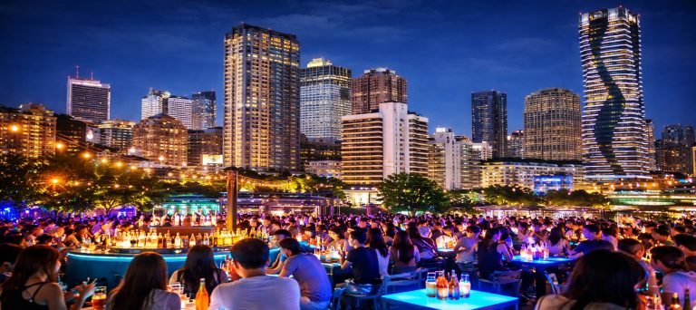 Rooftop bar in Taichung at night with glowing city skyline, high-rise buildings, and lively nightlife crowd.