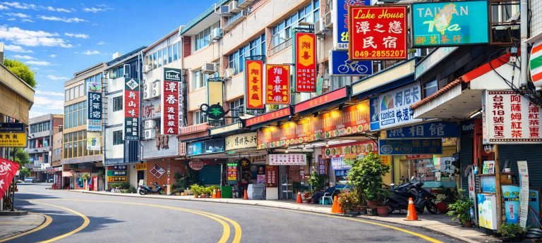 Colorful street in Ita Thao, Sun Moon Lake with Taiwanese shop signs, small hotels, tea houses and restaurants on a sunny day in Taiwan.