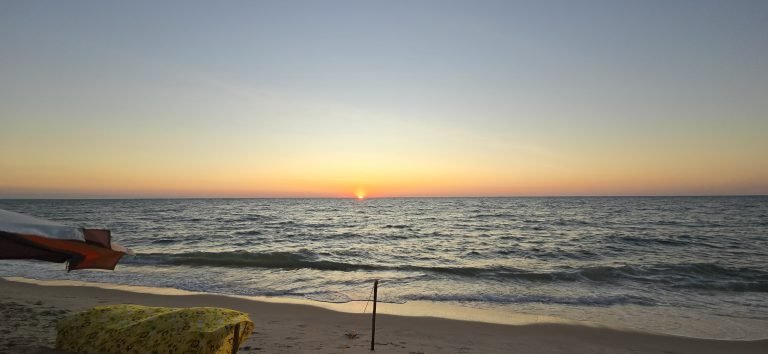 Sunset over the ocean in Southern Madagascar with gentle waves rolling onto a quiet sandy beach.