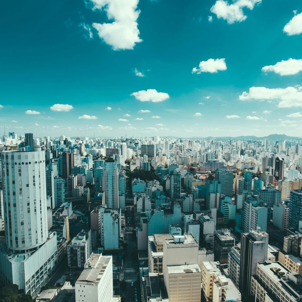 Sunny aerial view of São Paulo skyline with dense high-rise buildings under blue skies.