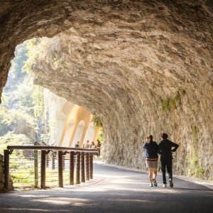 Sunlit tunnel walkway in Taroko Gorge with visitors walking along a marble rock passage in Hualien, Taiwan