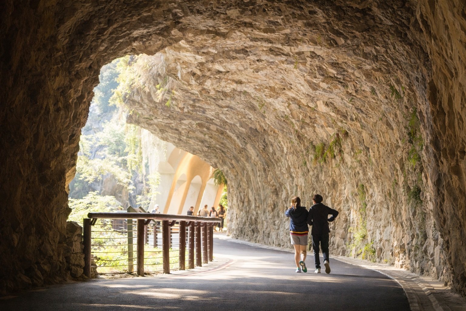 Sunlit tunnel walkway in Taroko Gorge with visitors walking along a marble rock passage in Hualien, Taiwan