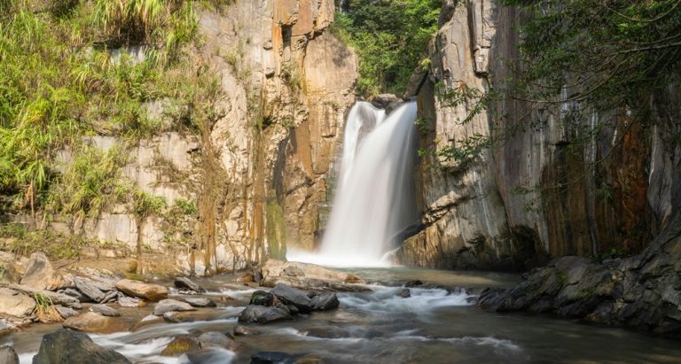 Waterfall flowing through rocky cliffs in Taroko Gorge Taiwan surrounded by marble canyon walls and forest