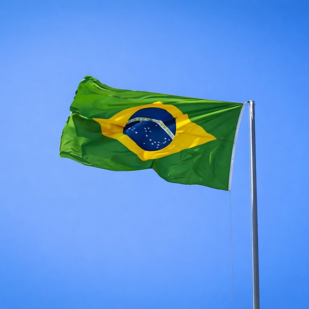 Brazilian flag waving on a flagpole against a clear, bright blue sky on a sunny day.