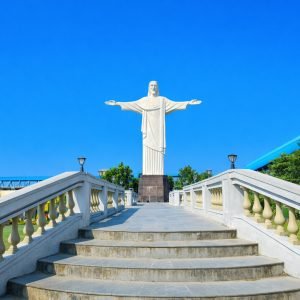 Replica of Christ the Redeemer statue with blue sky and stone stairway leading up to the monument