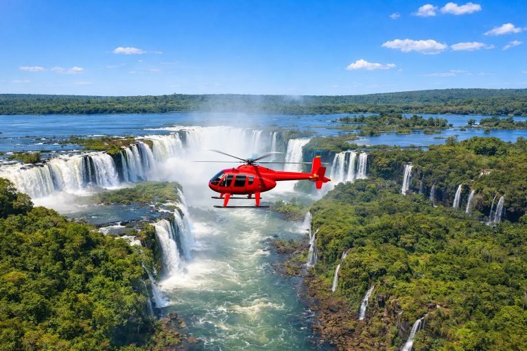 Helicopter flying over Iguazu Falls in Brazil on a sunny afternoon with bright blue skies and panoramic waterfall views