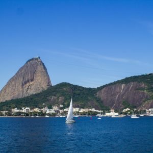Sugarloaf Mountain Rio de Janeiro seen across Guanabara Bay with sailboat in foreground and Urca neighborhood below