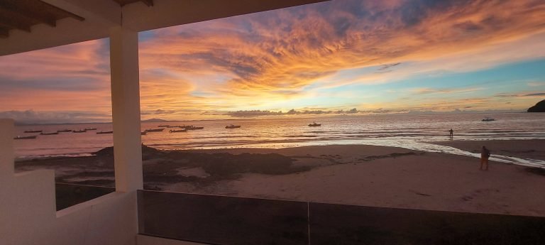 Coucher de soleil sur la plage à Madagascar vu depuis une terrasse avec bateaux de pêche